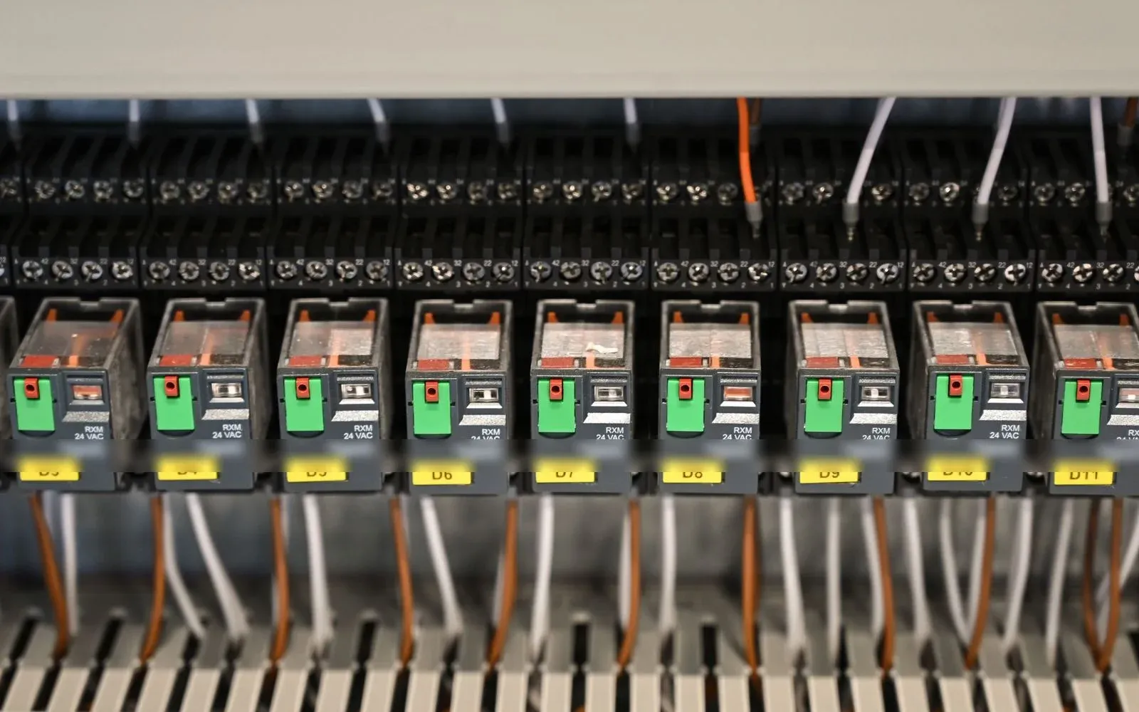 A row of control relays and numbered terminal blocks with neat wiring in an industrial control panel.