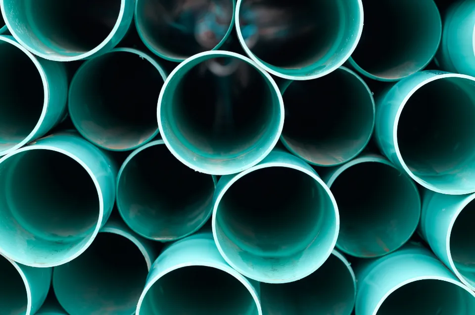 A stack of teal-painted process pipes at an industrial plant.